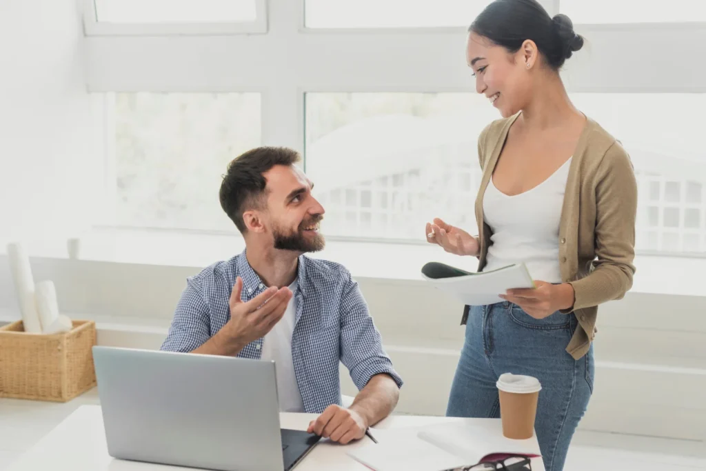 10 Consejos para Iniciar una Conversación con Confianza 1 Un hombre sentado en un escritorio frente a una computadora portátil tiene una conversación con una mujer