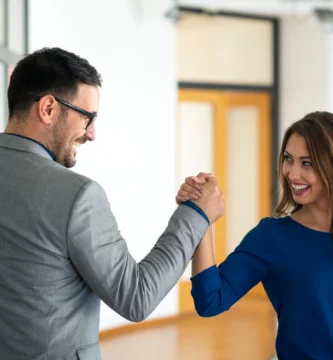 Un hombre y una mujer se saludan con un apretón de manos, indicando una interacción con confianza.